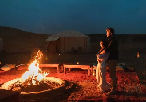 Couple hug in love near big campfire. Romantic night in glamping desert camp in Sahara, Morocco T