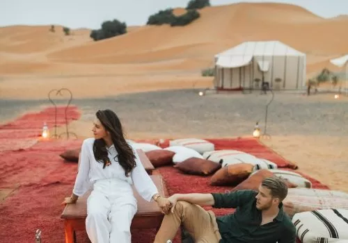 Stylish european couple in love enjoying evening together in luxury glamping camp in Sahara desert